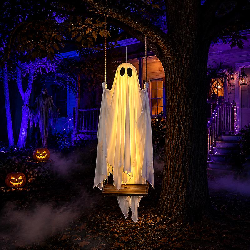 Illuminated draped ghost on its hanging swing, styled beside a Halloween display